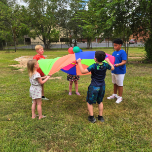 Children playing with colorful parachute outdoors
